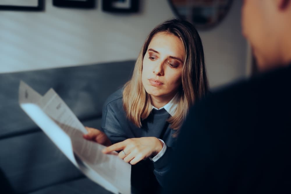 Female presenting and discussing documents with her partner, reviewing the terms of an agreement contract together.