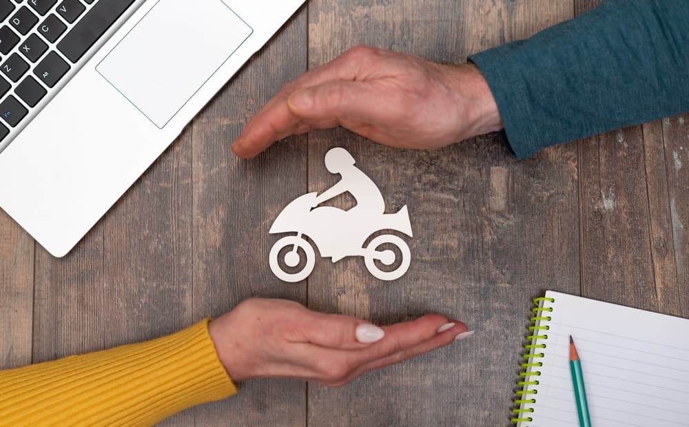 Two hands around a motorcycle cutout on a desk, representing a lawyer examining a traffic accident.