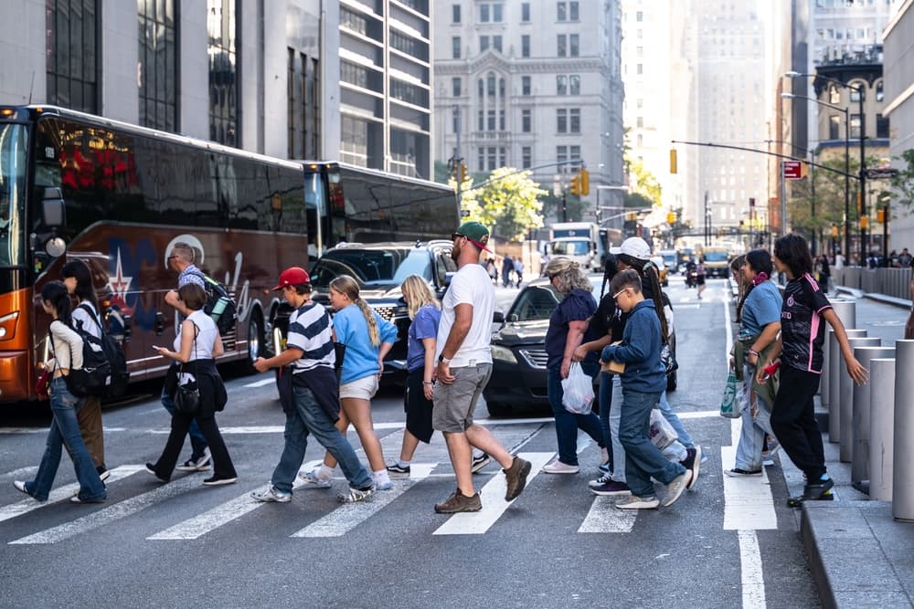 Pedestrians bustling across a city street, forming a vibrant and energetic crowd in motion.