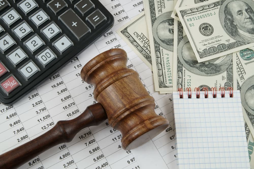 Business essentials: Calculator, judge gavel, money, and documents symbolizing financial decisions and legal matters.