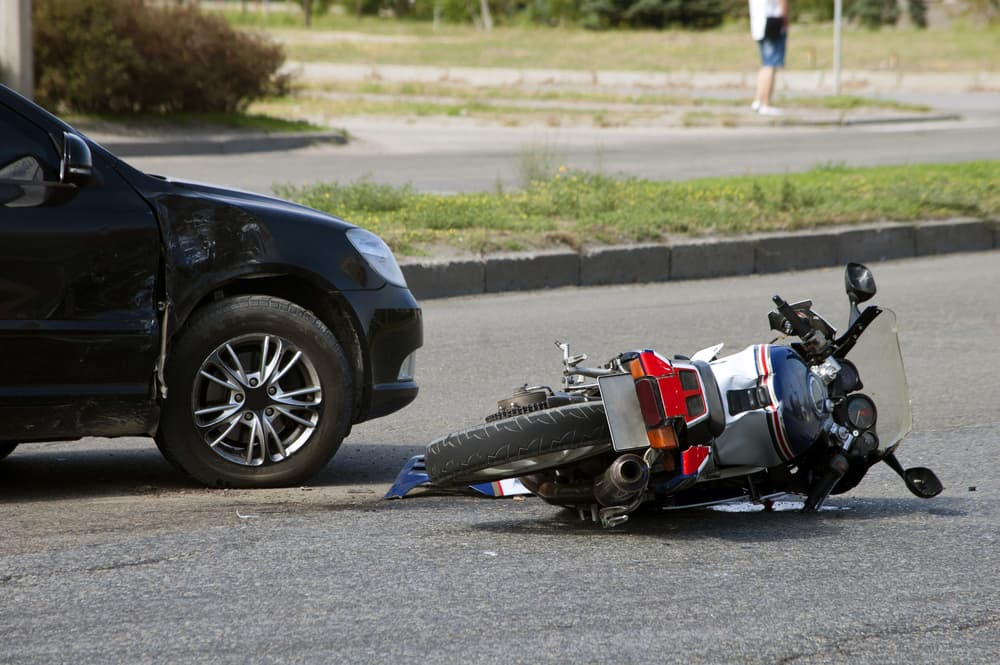 Motorcycle down after collision with car; settlements often depend on specific case factors and damages.