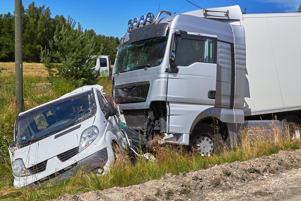 Damaged van aftermath of collision with a large truck, illustrating a transportation accident scenario.