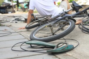 Man, bicycle, and shoes lie near a power pole crash on the road after an accident.