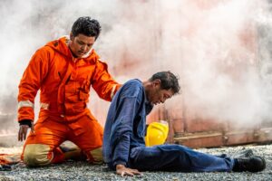 Focused firefighter in safety gear aids man overcome by smoke in burning building. Safety, rescue, and healthcare concept.