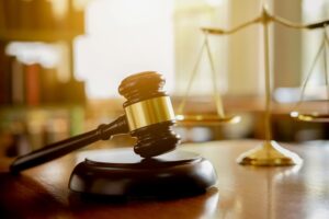 A judge's gavel with legal professionals having a team meeting at a law firm in the background. Legal concepts.