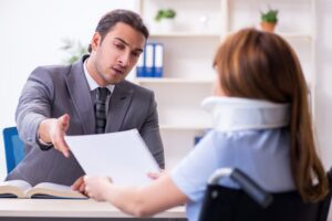 Young woman with injury accompanied by male lawyer in courtroom for legal proceedings.