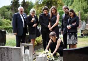 The family lays flowers upon the grave, their hearts heavy with sorrow as they mourn the wrongful death resulting from the tragic accident.