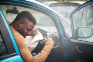 An injured motorist sitting in a car after a crash with the airbag deployed.