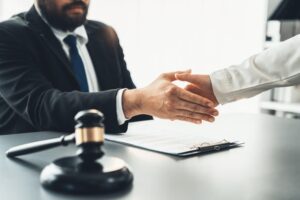 Close-up of lawyers shaking hands after successful legal discussion on contract agreement for a lawsuit.