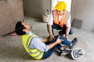 An engineer injured at work receiving assistance from colleagues. Safety in construction zones.