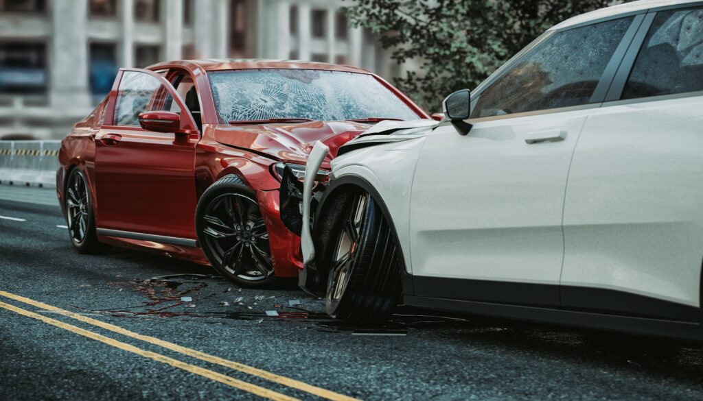 Head-on car accident between red and white vehicles with severe front-end damage on city street.