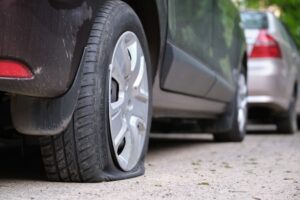 Car with a flat tire parked on the side of the road.