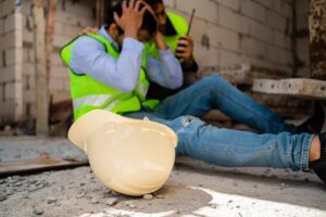 A workplace accident involving a construction worker at a job site. Emphasizing safety and rescue efforts to protect the injured. Security concept with a focus on the helmet.