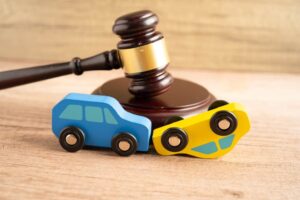 Gavel beside a car model symbolizing a car accident lawsuit and insurance claims. Legal justice and compensation concept for vehicle-related disputes.