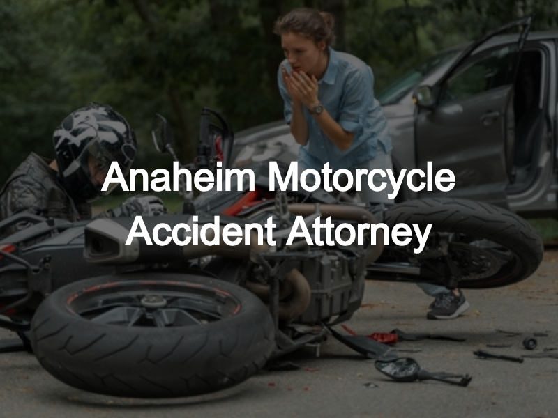 A concerned woman kneels beside an injured motorcyclist after a collision with a car in Anaheim, with a damaged motorcycle lying on its side in the foreground.