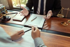 Attorney consulting with client over legal documents at a law office desk with gavel and scales of justice