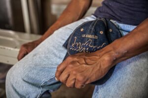 Undocumented construction worker sitting with a Los Angeles cap in hand, symbolizing workplace injury concerns and legal rights in California.