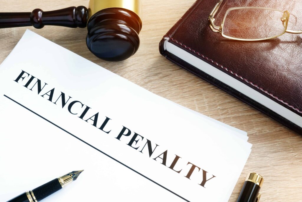 Document labeled financial penalty on desk with judge’s gavel, notebook, and pen symbolizing legal fines and court sanctions.