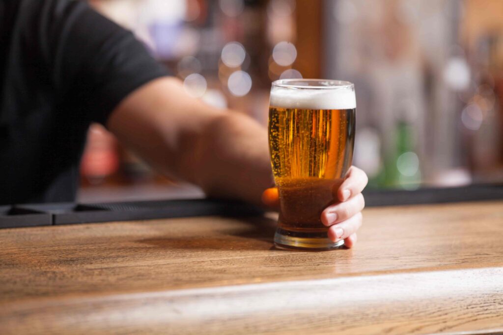 Bartender serving a glass of beer on a bar counter in a pub or restaurant.