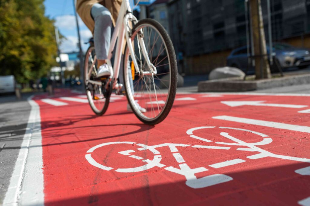 Cyclist riding bike on designated red bicycle lane in urban city street.