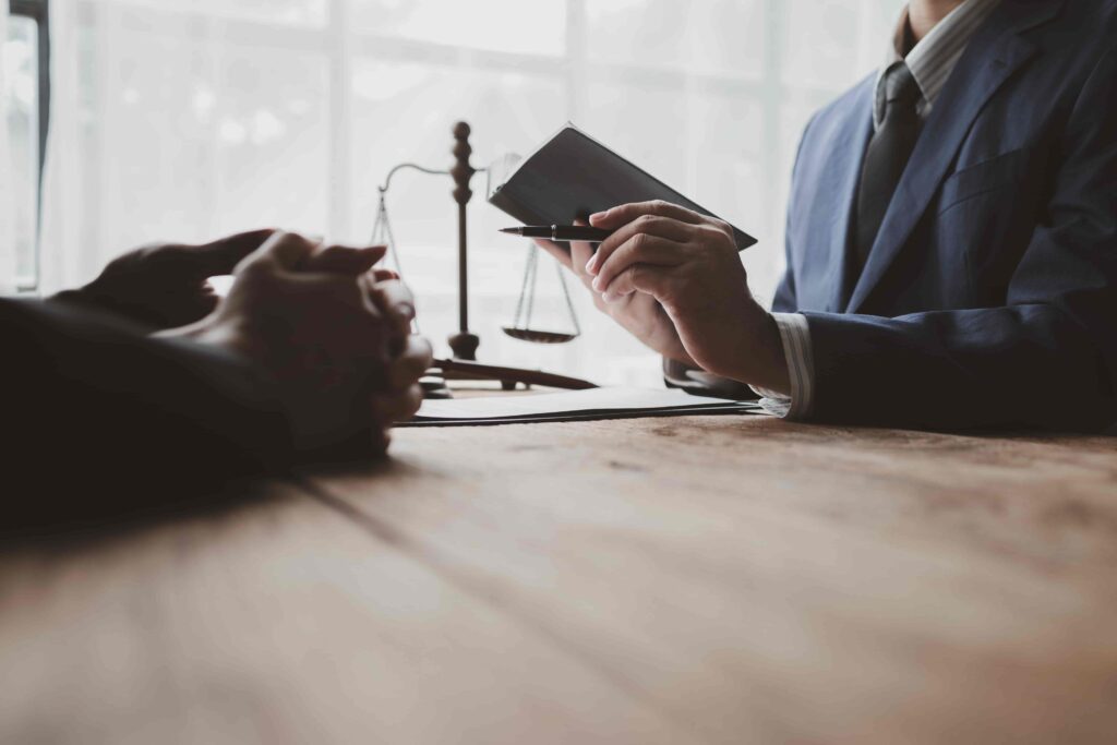 Lawyer consulting with client in office with legal documents and scales of justice.