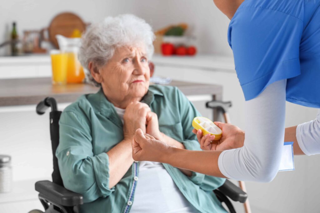 Concerned elderly woman in a wheelchair interacting with caregiver offering medication in a home care setting. Concerned elderly woman in a wheelchair interacting with caregiver offering medication in a home care setting.